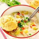 Soup in bowl with biscuit on the edge.