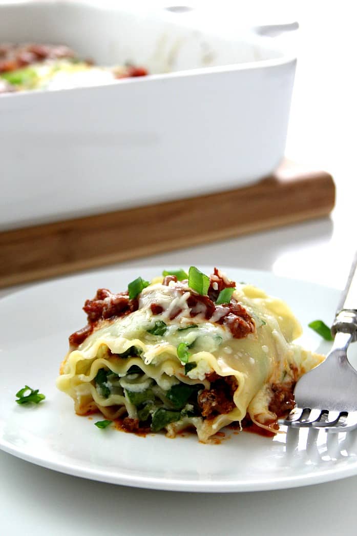 Side shot of one lasagna roll-up on plate.