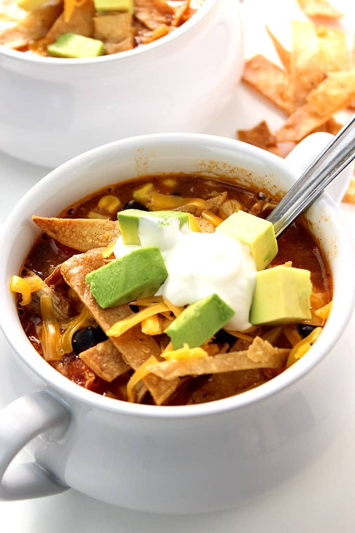 Side shot of soup bowl with handles with chicken enchilada soup.