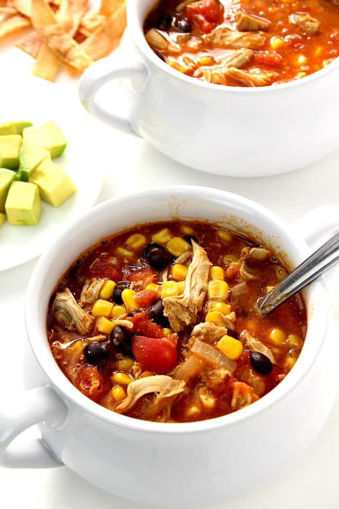 Overhead shot of chicken enchilada soup in two white soup bowls.