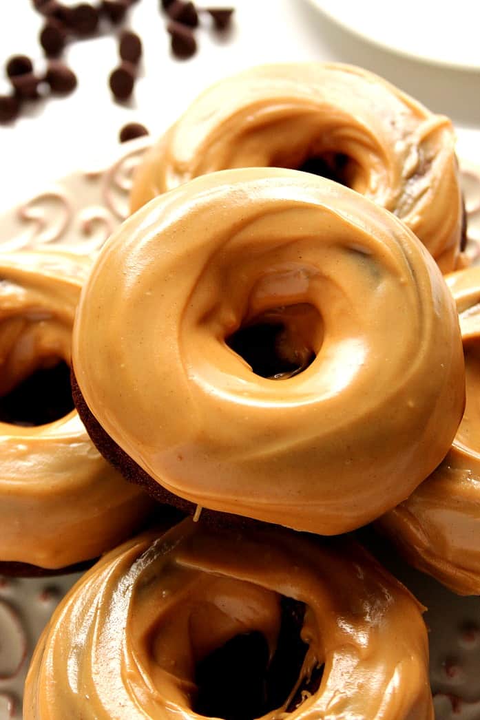 Overhead shot of chocolate donuts with smooth peanut butter glazed stacked on a plate. 