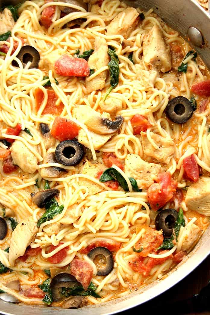 Close up shot of spaghetti pasta with chicken, tomatoes and olives. 
