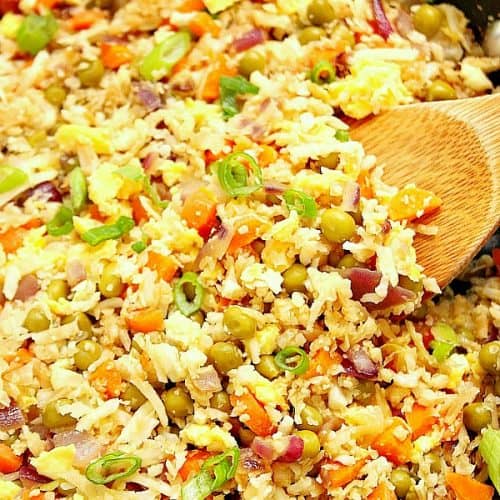 Cauliflower fried rice in skillet, with wooden spoon.