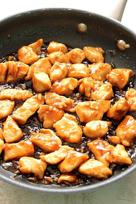 Side shot of chicken bites with teriyaki sauce in a non-stick skillet.