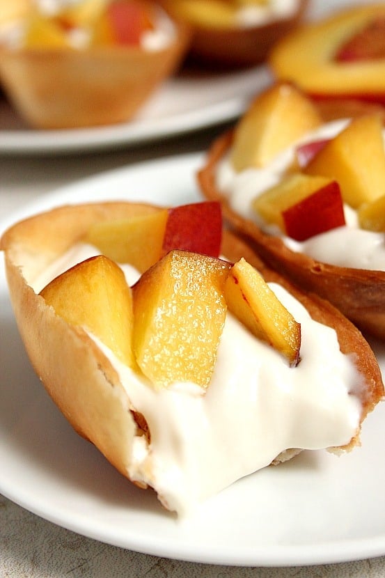 Peaches and Cream Dessert Taco Boats recipe - crispy tortilla taco boats filled with sweet and creamy cheesecake filling and topped with fresh, chopped juicy peaches. This quick and easy dessert disappeared quickly in our house! 