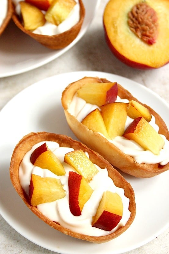 Peaches and Cream Dessert Taco Boats recipe - crispy tortilla taco boats filled with sweet and creamy cheesecake filling and topped with fresh, chopped juicy peaches. This quick and easy dessert disappeared quickly in our house! 