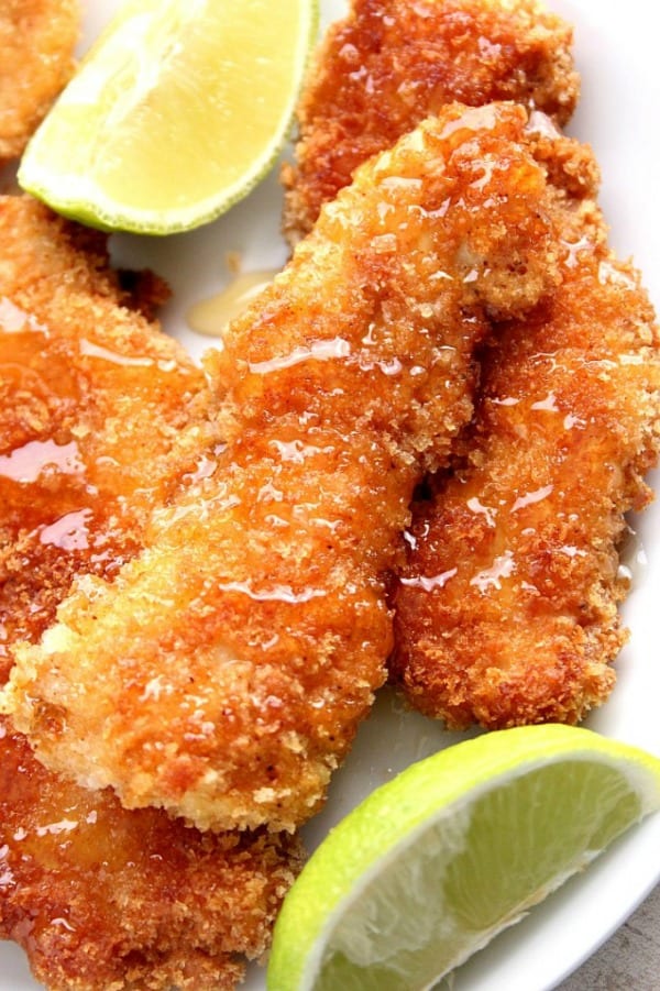Crunchy Honey Lime Chicken Recipe - crispy panko-crusted chicken tenders, drizzled with lime juice and sweet honey. This family friendly dinner idea is a huge hit every single time! Honey Lime Chicken Strips on plate.