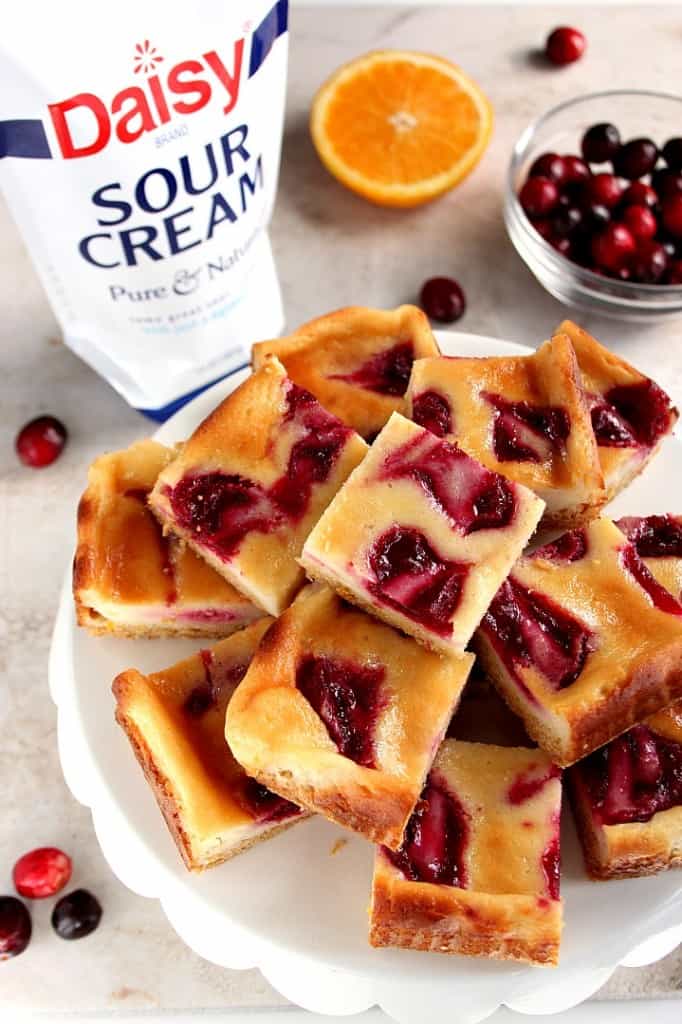 Cranberry Orange Sour Cream Bars recipe - easy dessert idea for the holidays! These sour cream bars with orange and cranberry jam swirls baked on a cookie crust will look festive on any holiday table.
