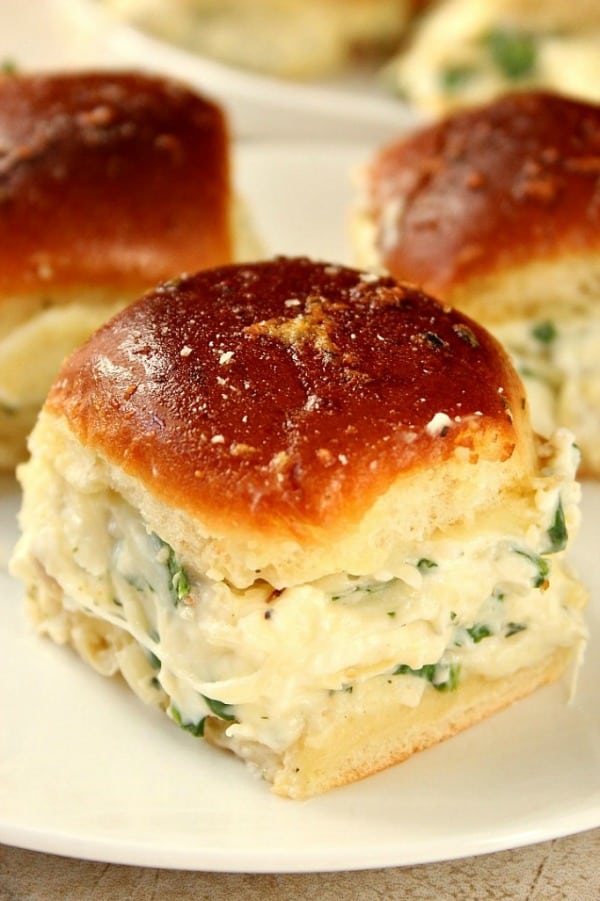 Cheesy Spinach Artichoke Dip Sliders recipe - baked garlic butter slider buns with spinach artichoke dip and cheese. Taking dip to a new level for one amazing party appetizer! Spinach Dip Sliders on a plate.