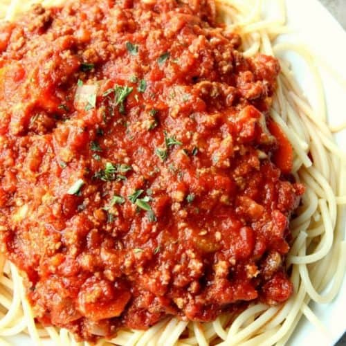 Slow Cooker Bolognese Sauce over spaghetti on plate.