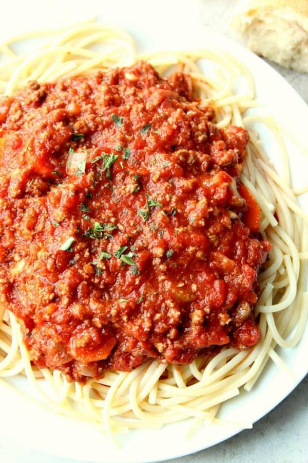 Slow Cooker Bolognese Sauce over spaghetti on plate.