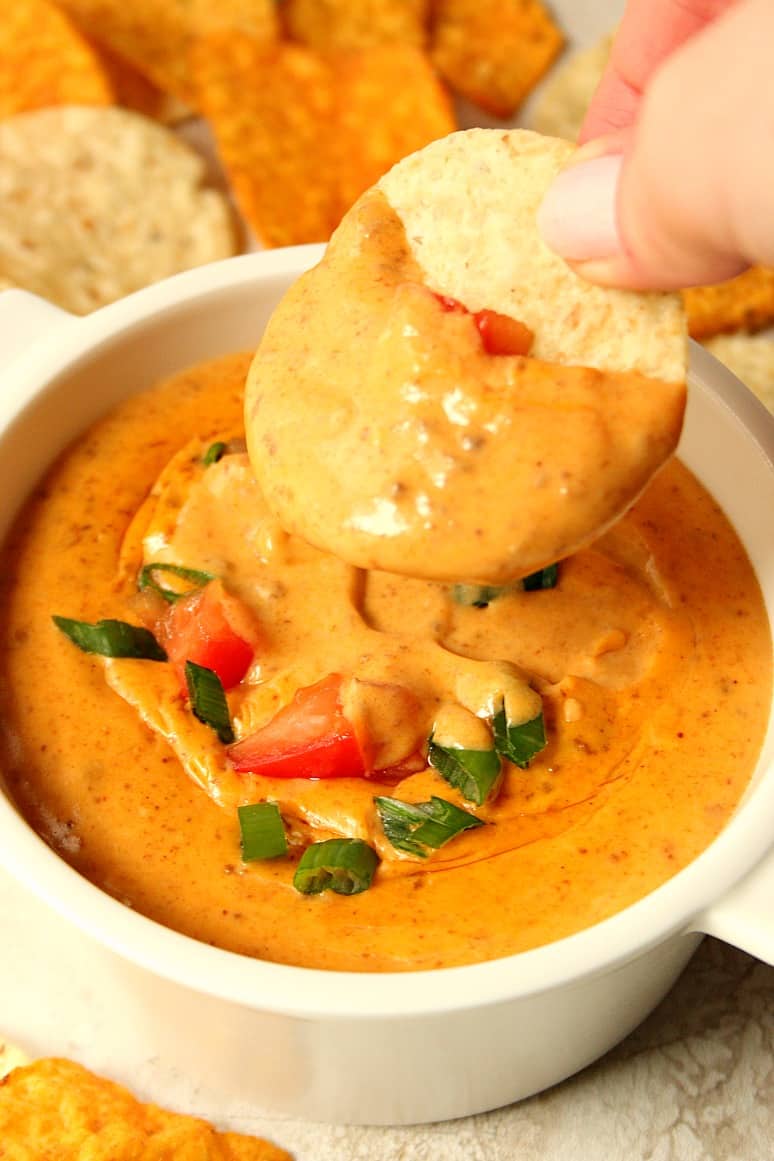 queso in a bowl, hand holding a chip