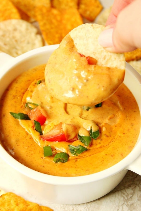 Chili Queso Dip Recipe Dip in white bowl with dipped tortilla chip.