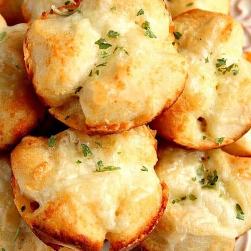 Garlic Parmesan Pull-Apart Rolls stacked up on white plate.