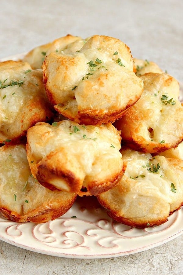 Several pull-apart rolls with garlic and Parmesan cheese on white plate.