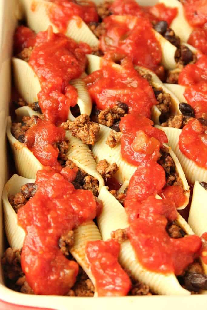 Overhead shot of pasta shells stuffed with taco meat and tomato meat in casserole dish.