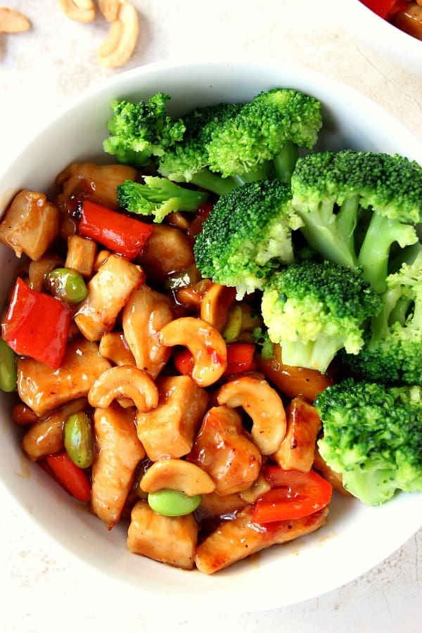 Chicken with cashews and broccoli in white bowl.