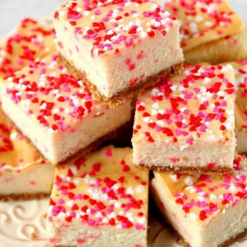 Funfetti Cheesecake Bars stacked up on a white plate.