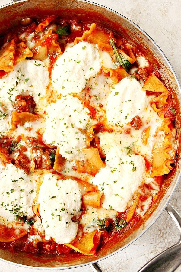 This Easy One Pan Lasagna is a quick and easy skillet version of everyone's favorite dish. Made in just 30 minutes with Italian sausage, delicious sauce, lasagna noodles and topped with cheese! Overhead shot of lasagna in deep skillet.