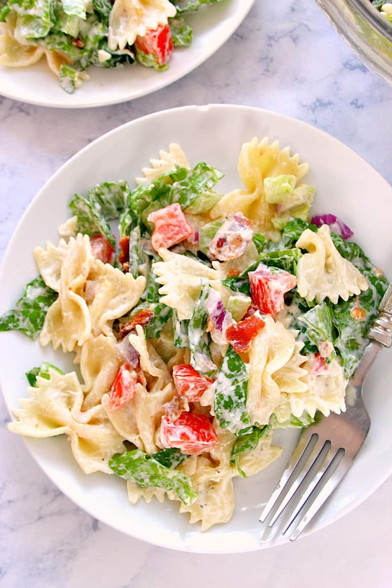 Overhead shot of BLT pasta salad on white plate, with fork on side.