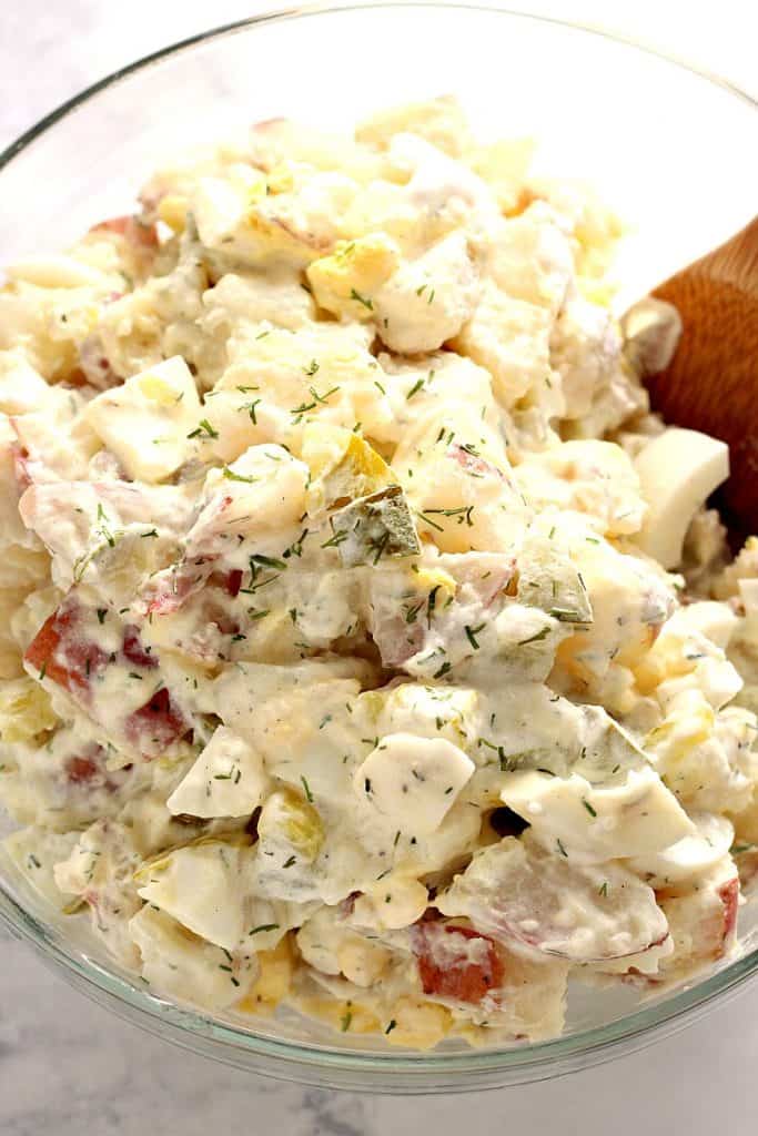 Dill pickle potato egg salad in glass mixing bowl.