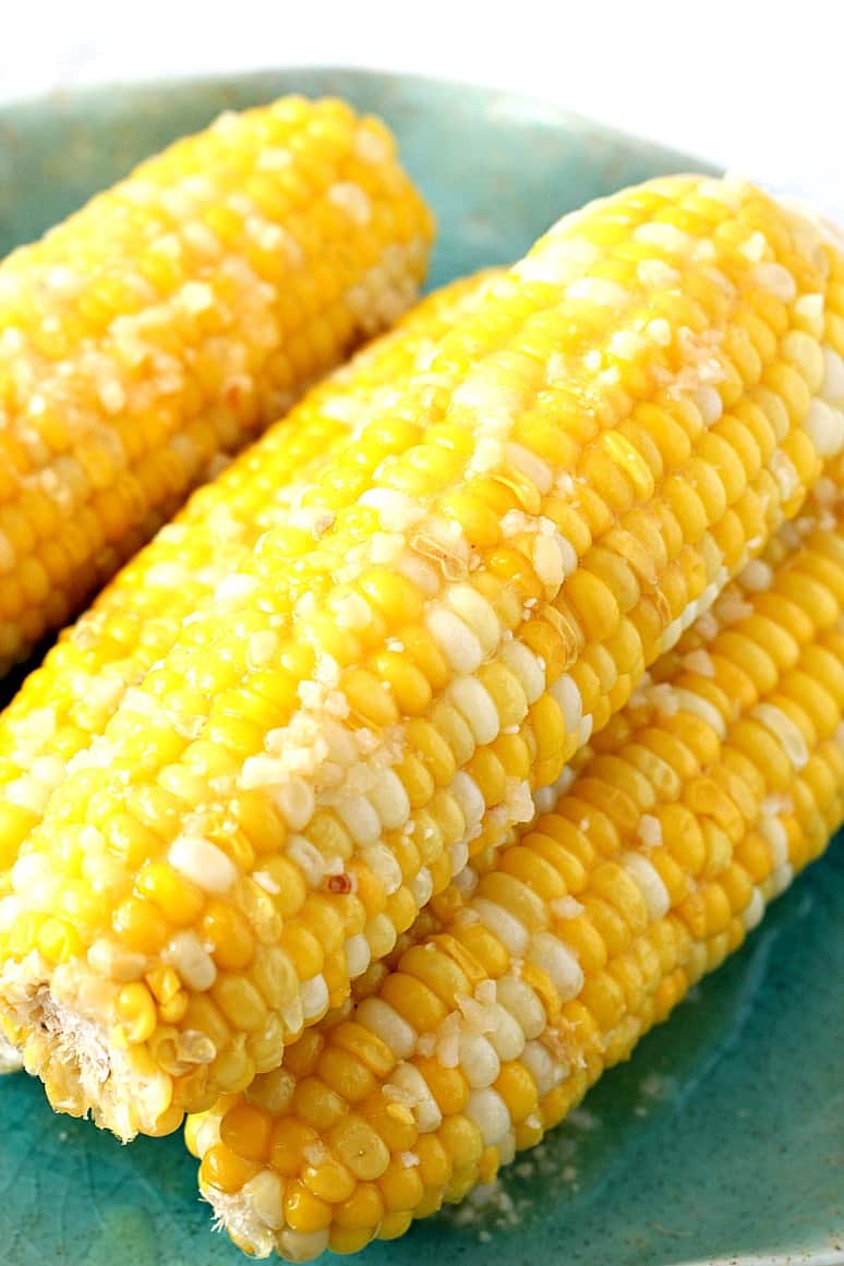 Side close up shot of corn on the cob on green plate. 