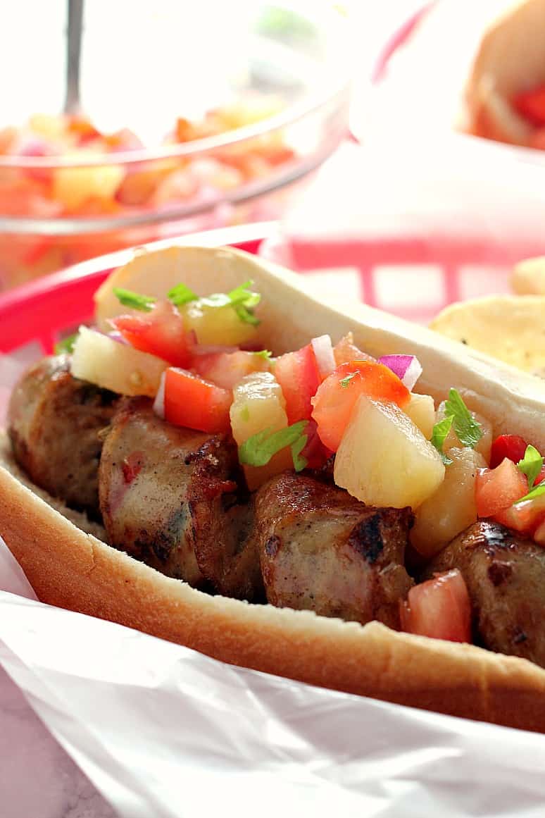 Grilled Chicken Sausage with Pineapple Salsa Recipe - spiral cut grilled sausage is paired with fresh, sweet and savory topping of pineapple, tomatoes, red onion and bell pepper. Perfect Summer picnic food!