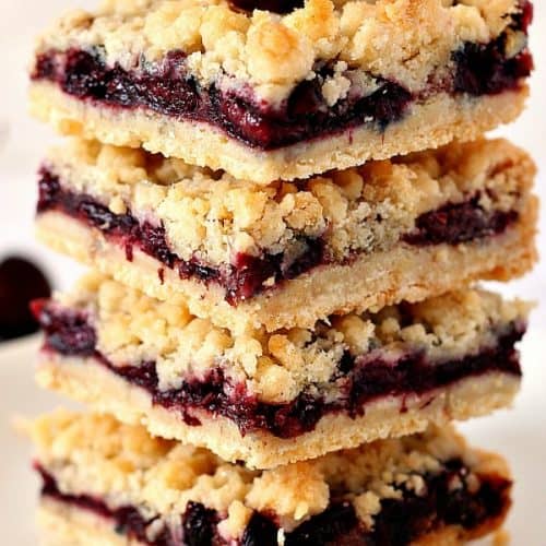 Cherry Pie Crumb Bars in a stack with fresh cherry on top.