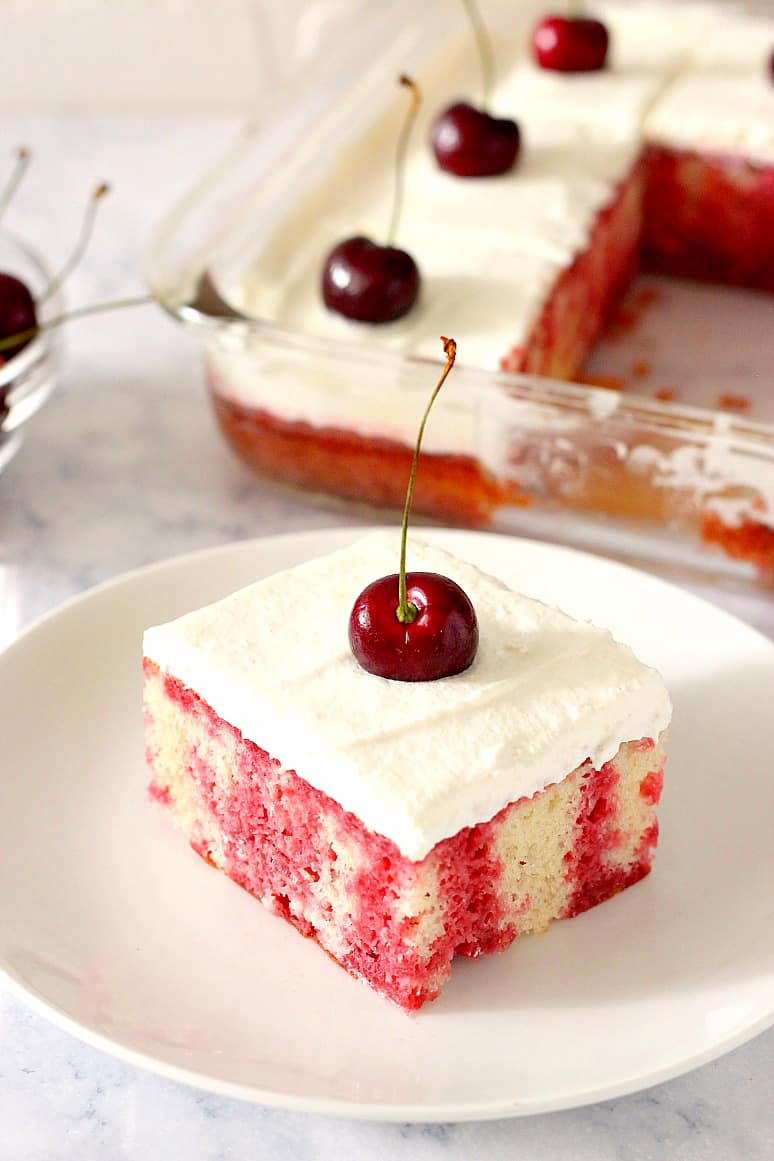 Cherry Poke Cake Recipe - fluffy vanilla cake with dark cherry jello, topped with whipped cream topping and fresh sweet cherries. This is the one summer dessert you have to try! 