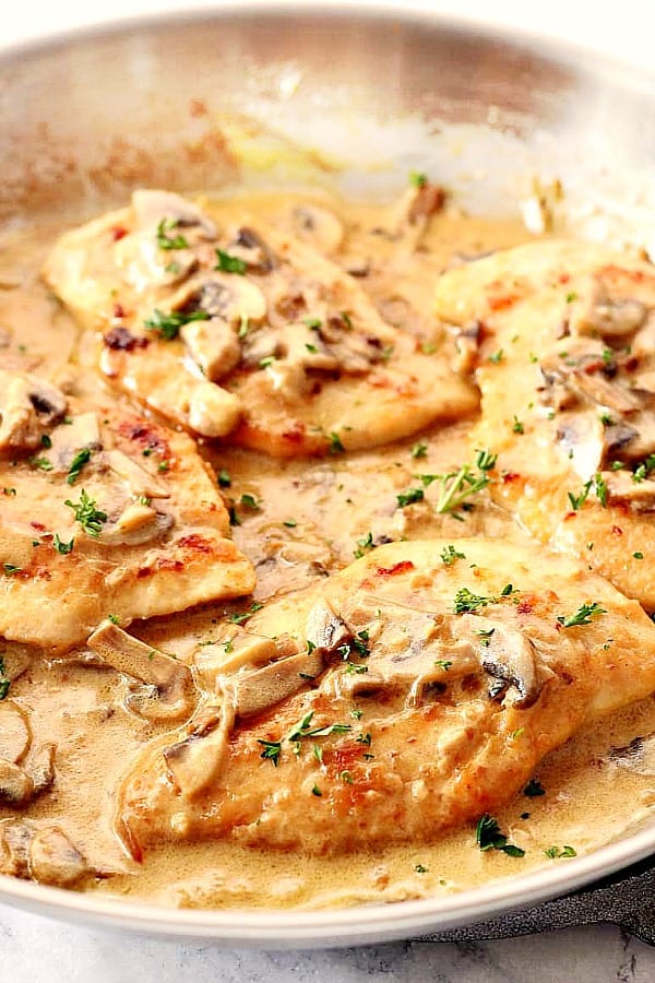 Creamy Mushroom Garlic Chicken cutlets in a pan with sauce.