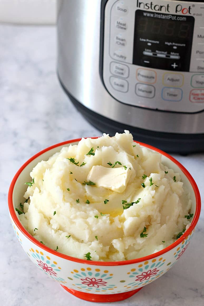 Side shot of mashed potatoes in small bowl, next to Instant Pot.