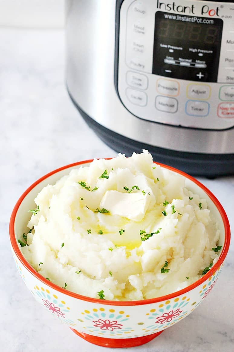 Side shot of mashed potatoes in bowl, next to Instant Pot.