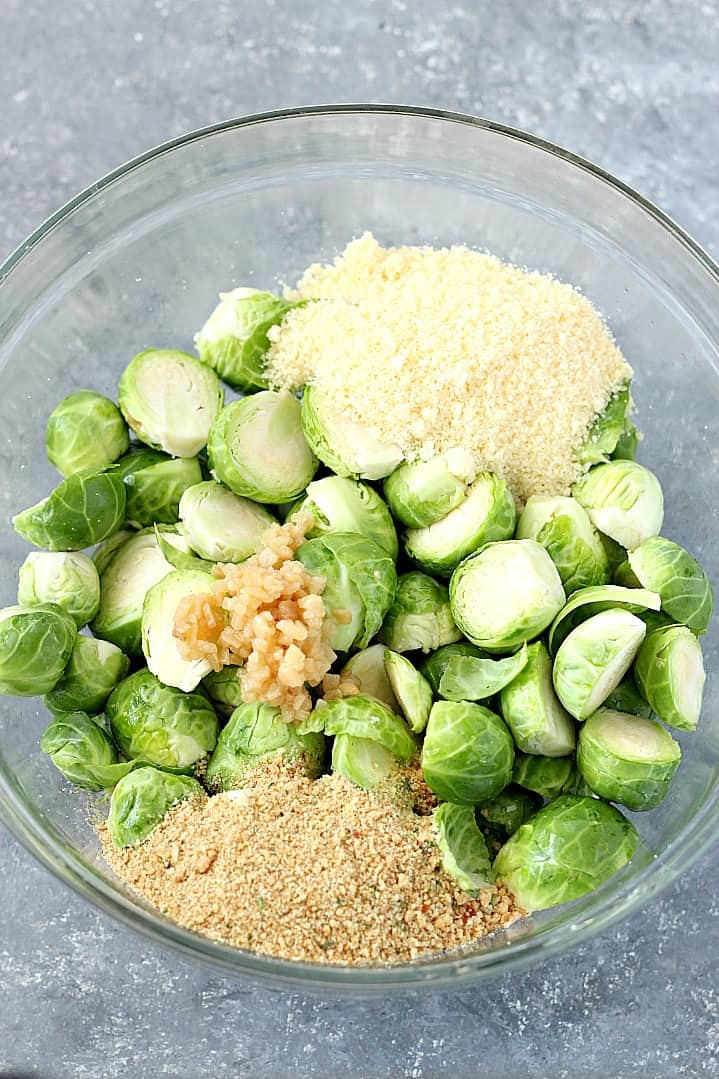 Ingredients for roasted Brussels sprouts in a glass bowl.