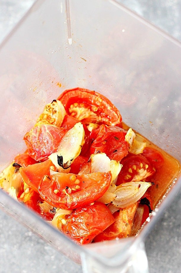 Overhead shot of roasted tomatoes and onions in blender jar.