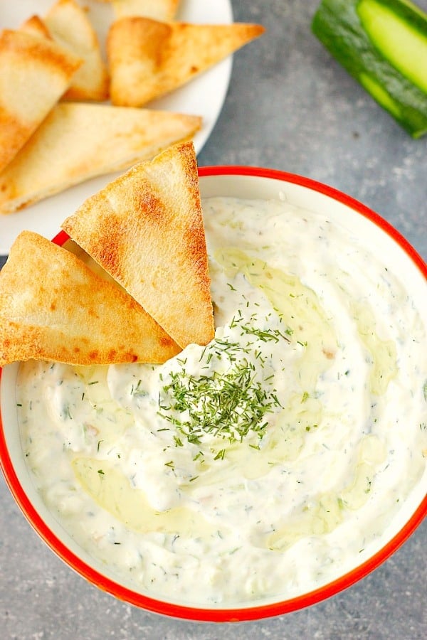 Overhead shot of cucumber dip in bowl with red rim.