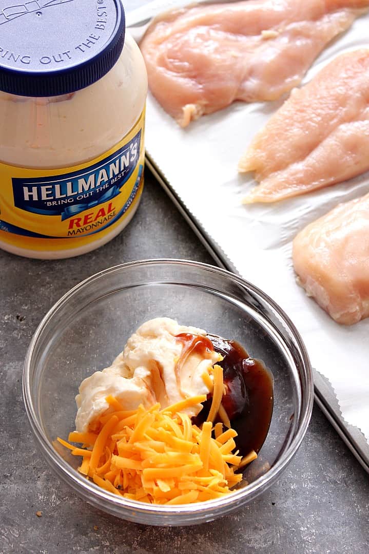 Overhead shot of chicken breast on sheet pan, mayo, BBQ sauce and cheddar in glass bowl.