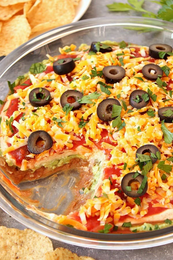 Mexican Layer Dip - quick and easy 5-layer dip with refried beans, guacamole, seasoned sour cream, salsa and cheese. Perfect for parties! Mexican 5 Layer Dip in glass pie plate.