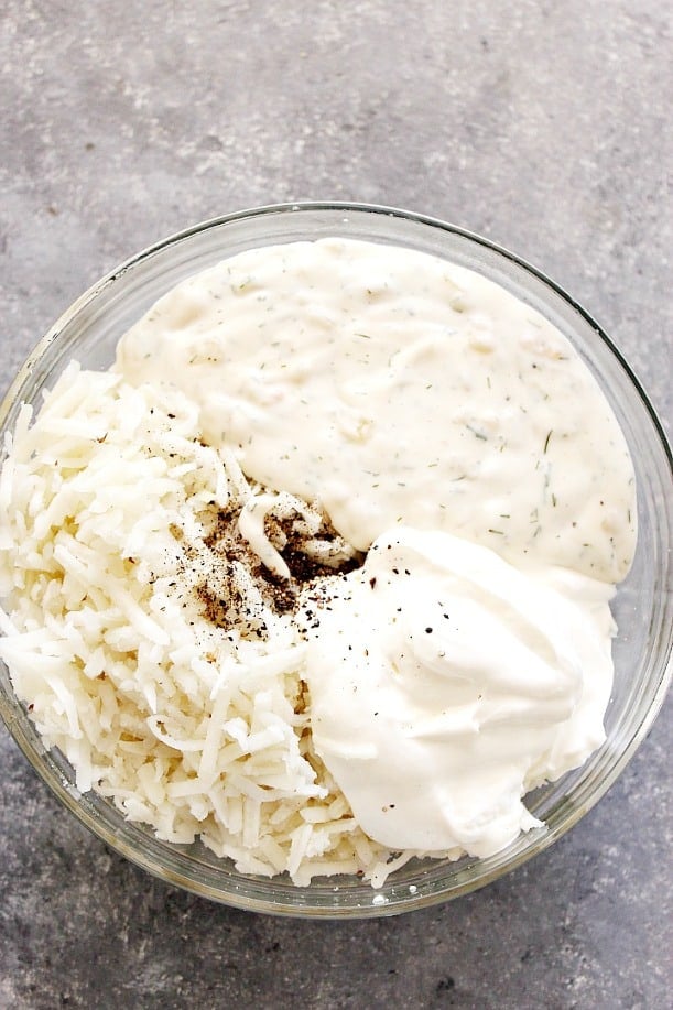 Overhead shot of hashbrowns, sour cream and homemade cream of soup in glass bowl.