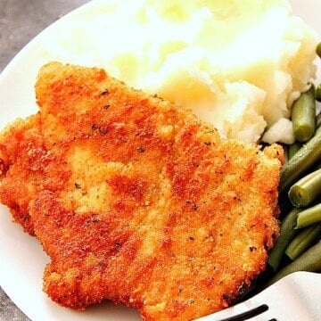 Breaded pork cutlet with mashed potatoes on plate.