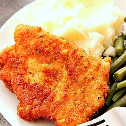 Breaded pork cutlet with mashed potatoes on plate.