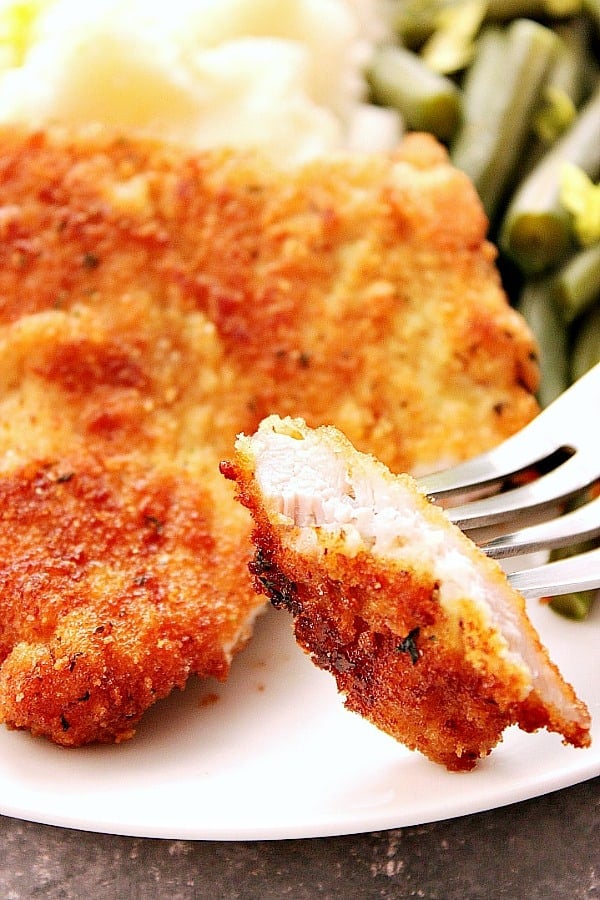 Close up shot of a small cut piece of pork schnitzel on fork.