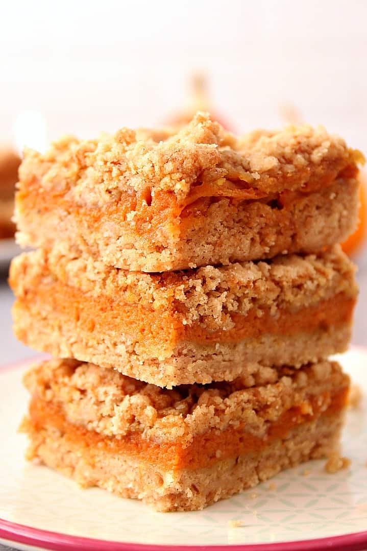 Side close up shot of three pumpkin pie bars stacked up on each other on plate.