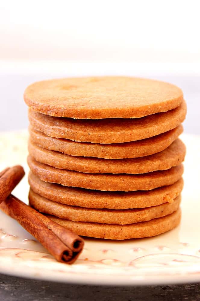 Side shot of a stack of thin shortbread cookies with cinnamon sticks. 