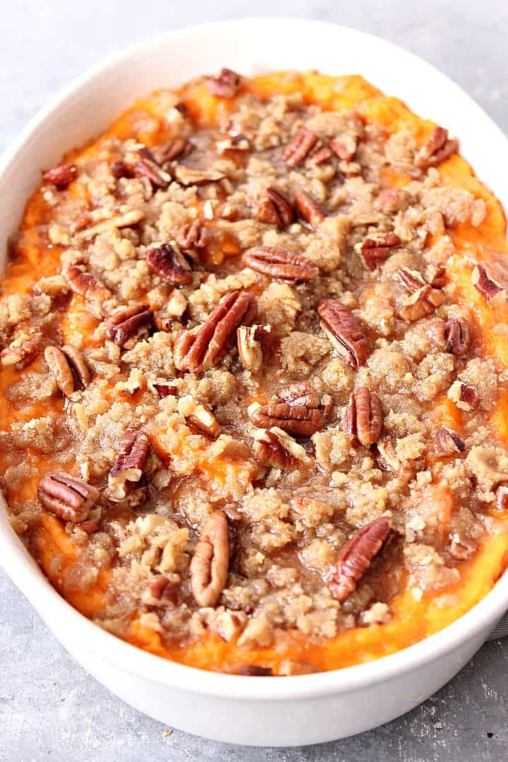 Close up shot of baked sweet potato casserole, topped with pecans and brown sugar.