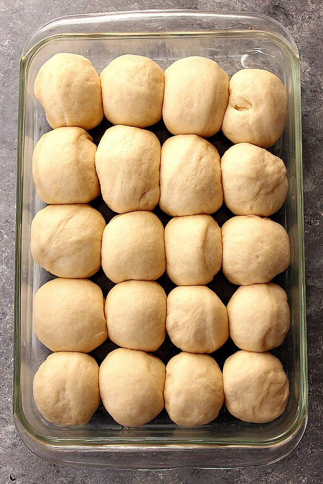 The dinner rolls dough arranged in baking pan.