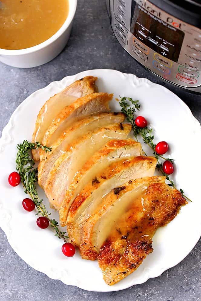 Overhead shot of sliced turkey breast on white serving plate, with Instant Pot in the background.