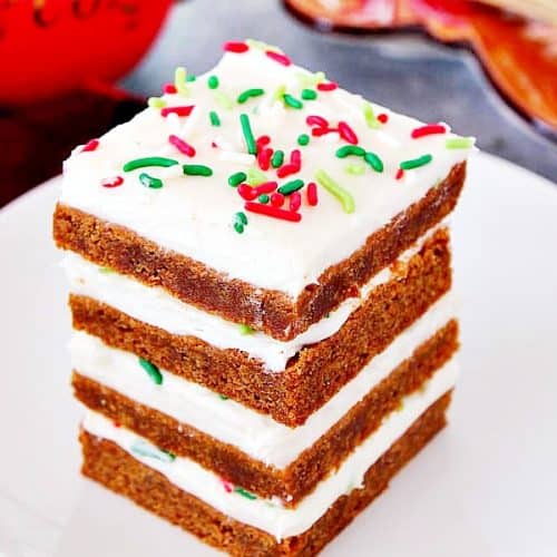 Gingerbread Bars with frosting stacked on white plate.