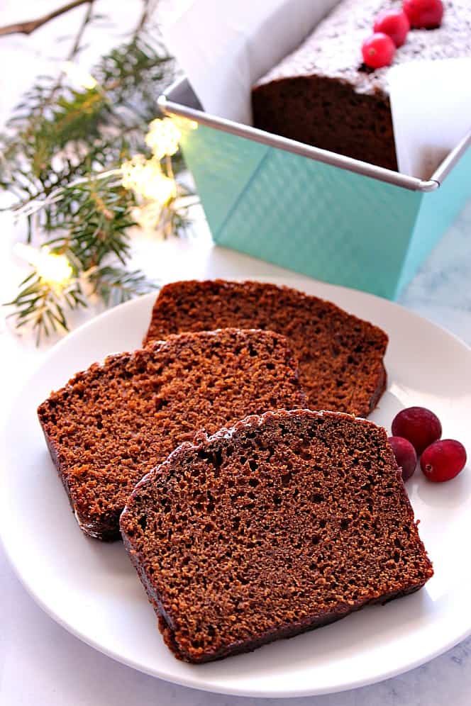 Side shot of gingerbread cake on white plate and in loaf pan.