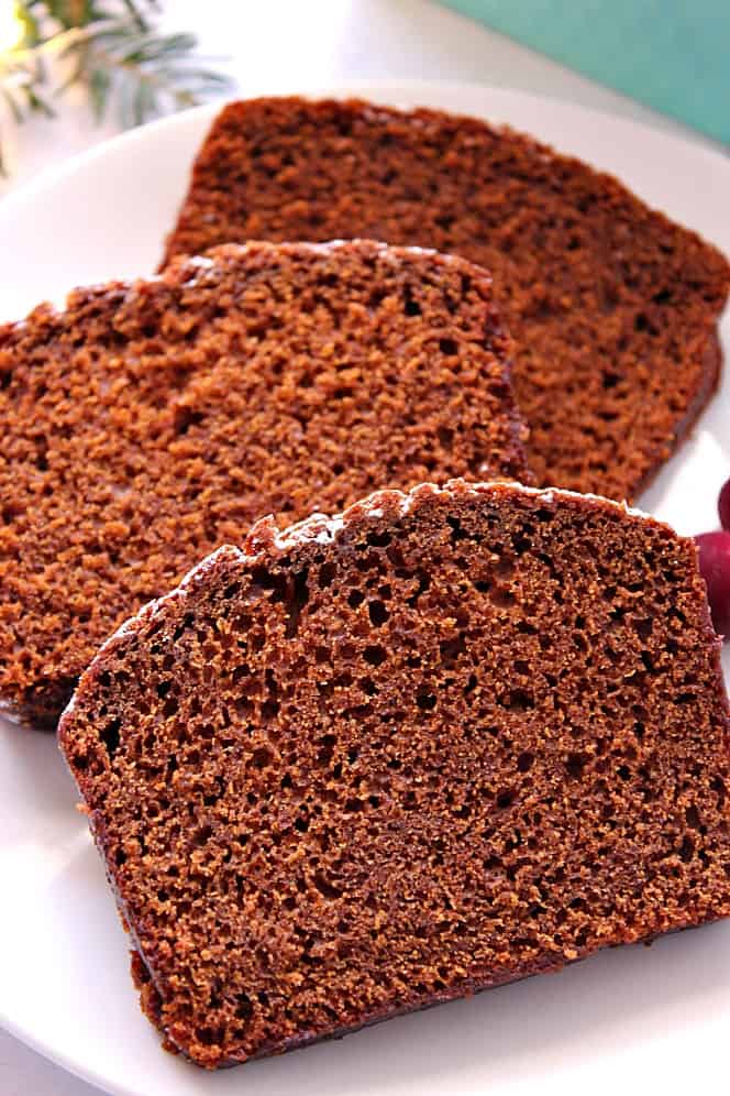 Close up side shot of three slices of gingerbread cake on white plate.