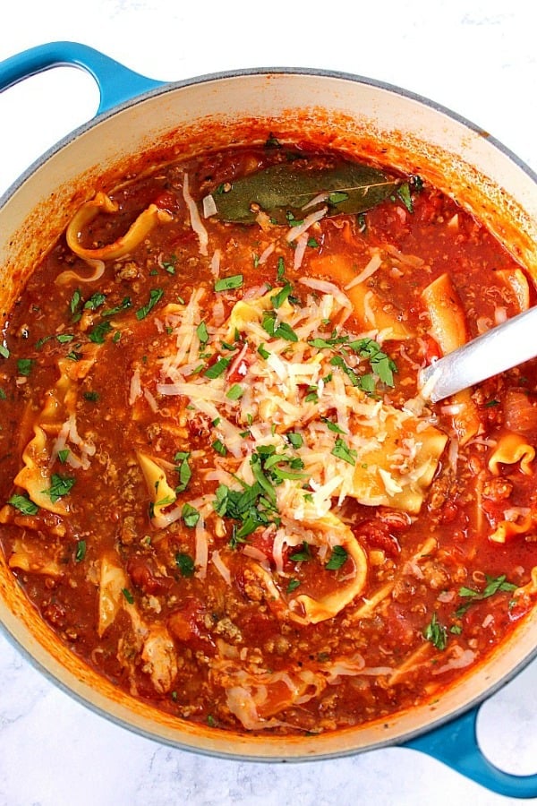 This Lasagna Soup is an easy and flavorful comfort food idea for busy days. Ground beef and noodles are cooked together in tomato based soup, then topped with ricotta and Parmesan cheese. Overhead shot of lasagna soup in Dutch oven.